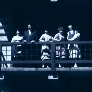 Group of people on outdoor balcony stairs, mid-20th century.