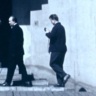 Group of people on outdoor balcony stairs, mid-20th century.