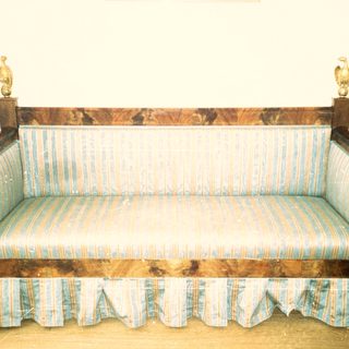 Antique wooden sofa with striped upholstery and ornate finials.