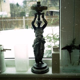 Vintage statue lamp beside winter window sill.