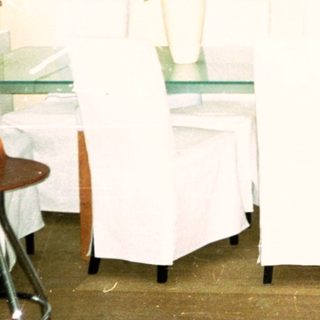 Minimalist room with white chairs, tables, art, and plants.