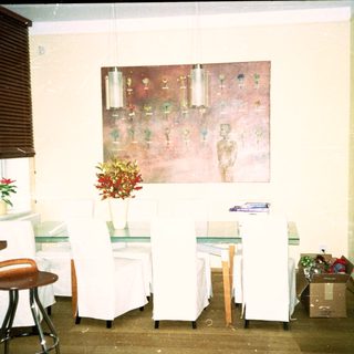Minimalist room with white chairs, tables, art, and plants.