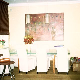 Minimalist room with white chairs, tables, art, and plants.