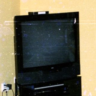 Empty room with old TV, damaged floor, and minimal furnishings.