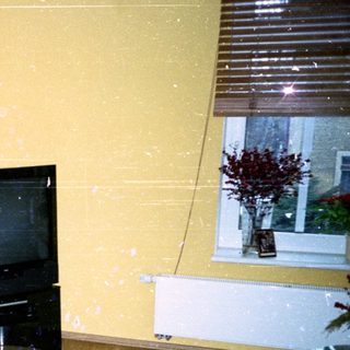 Empty room with old TV, damaged floor, and minimal furnishings.