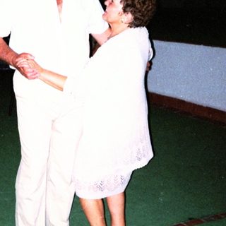 Couple dancing formally in white attire.