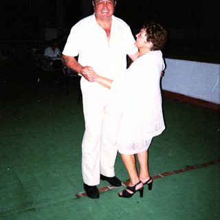 Couple dancing formally in white attire.