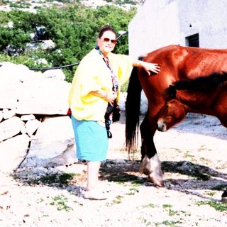 Person posing with horse near mountain restaurant.