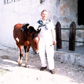Man standing beside a horse outside a restaurant.