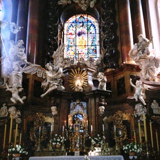 Baroque altar with ornate carvings, angels, stained glass.