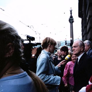 Public gathering with elderly man speaking to crowd near Nelson's Column.