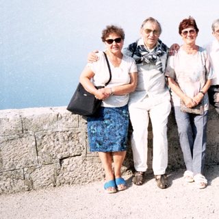 Four adults posing together outdoors by a stone wall.