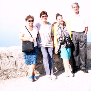 Four people posing together near a coastal cliff.