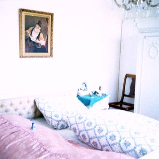 Classic bedroom with vintage bedding, framed portrait, and wooden furniture.