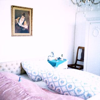 Classic bedroom with vintage bedding, framed portrait, and wooden furniture.