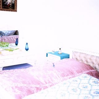 Vintage bedroom with twin beds, artwork, and decorative items.
