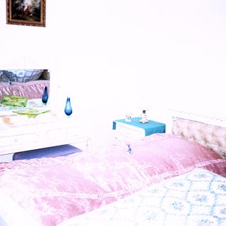 Vintage bedroom with twin beds, artwork, and decorative items.