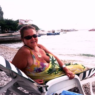 Woman relaxing on beach lounge by water.