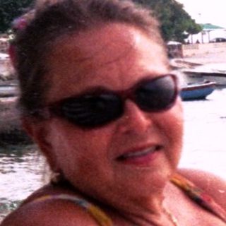 Woman relaxing on beach lounge by water.
