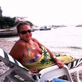 Woman relaxing on beach lounge by water.