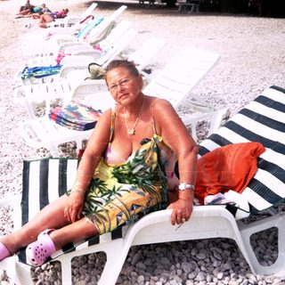 Woman relaxing on beach lounger by water.
