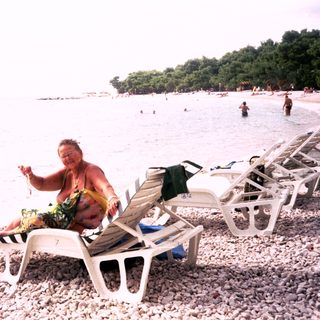 Person lounges on beach chair near ocean.