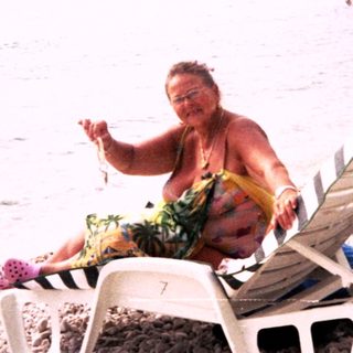 Person lounges on beach chair near ocean.