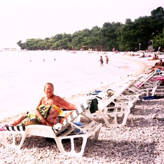 Beach scene with relaxed individuals lounging on sunbeds.
