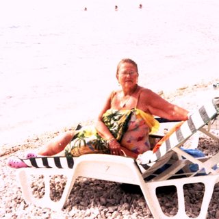 Beach scene with relaxed individuals lounging on sunbeds.