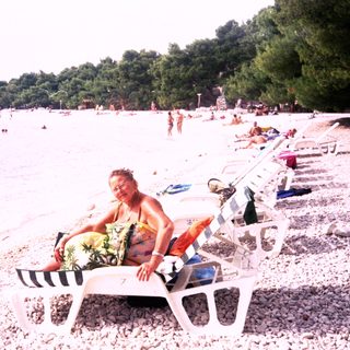 Peaceful beach scene with person relaxing on sun lounger.