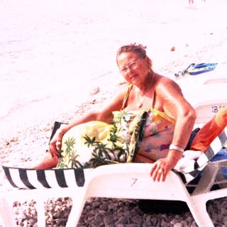 Peaceful beach scene with person relaxing on sun lounger.