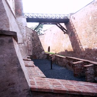 Abandoned brick courtyard with staircases and bridge.