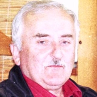 Man sitting indoors in a rustic restaurant setting.