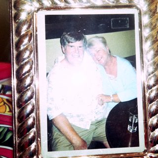 Two people posing together indoors in a framed photo.