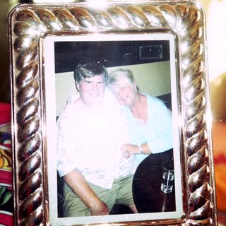 Two people posing together indoors in a framed photo.