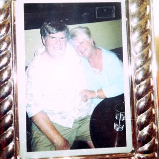 Two people posing together indoors in a framed photo.