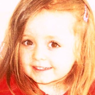 Young girl holding stuffed animals indoors.