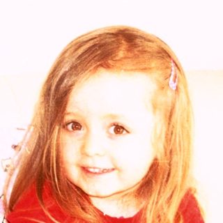 Young girl holding stuffed animals indoors.