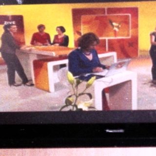 Flat-screen TV mounted in wall showing live broadcast.
