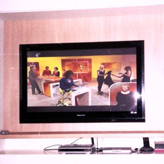Flat-screen TV mounted in wall showing live broadcast.