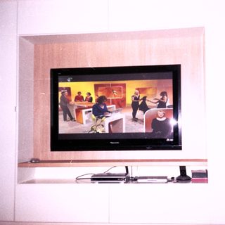 Flat-screen TV mounted in wall showing live broadcast.