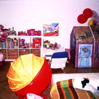 Playroom with colorful toys, bookshelf, playhouse, and seating.
