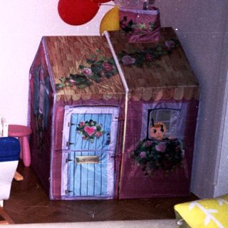 Playroom with colorful toys, bookshelf, playhouse, and seating.