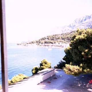 Scenic coastal view with mountains, sea, and greenery.
