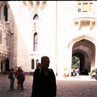 Woman walking with cane in historic courtyard.