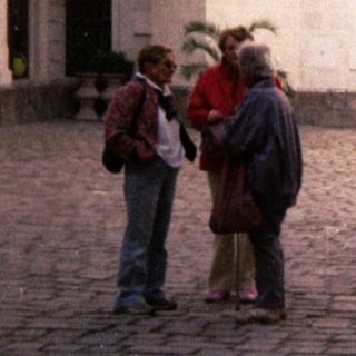 Woman walking with cane in historic courtyard.