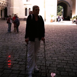 Woman walking with cane in historic courtyard.