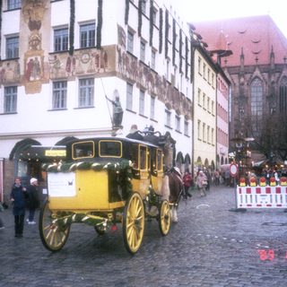 Historic horse-drawn carriage in European town square.