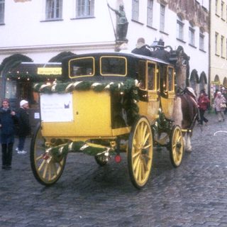 Historic horse-drawn carriage in European town square.