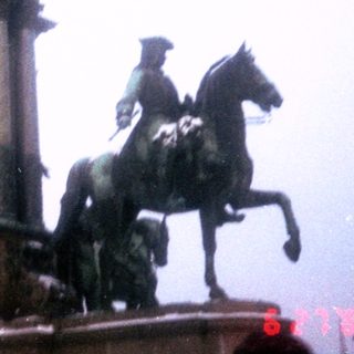 Equestrian monument with central seated figures and foggy background.